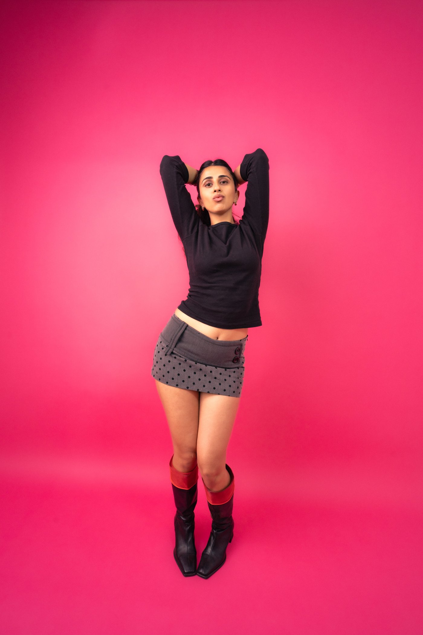 Ashna standing confidently with arms raised behind her head.